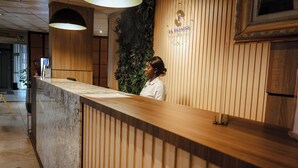 Un mostrador de recepción con detalles de madera, un logotipo en la pared y un cartel que indica la ubicación del salón de banquetes.