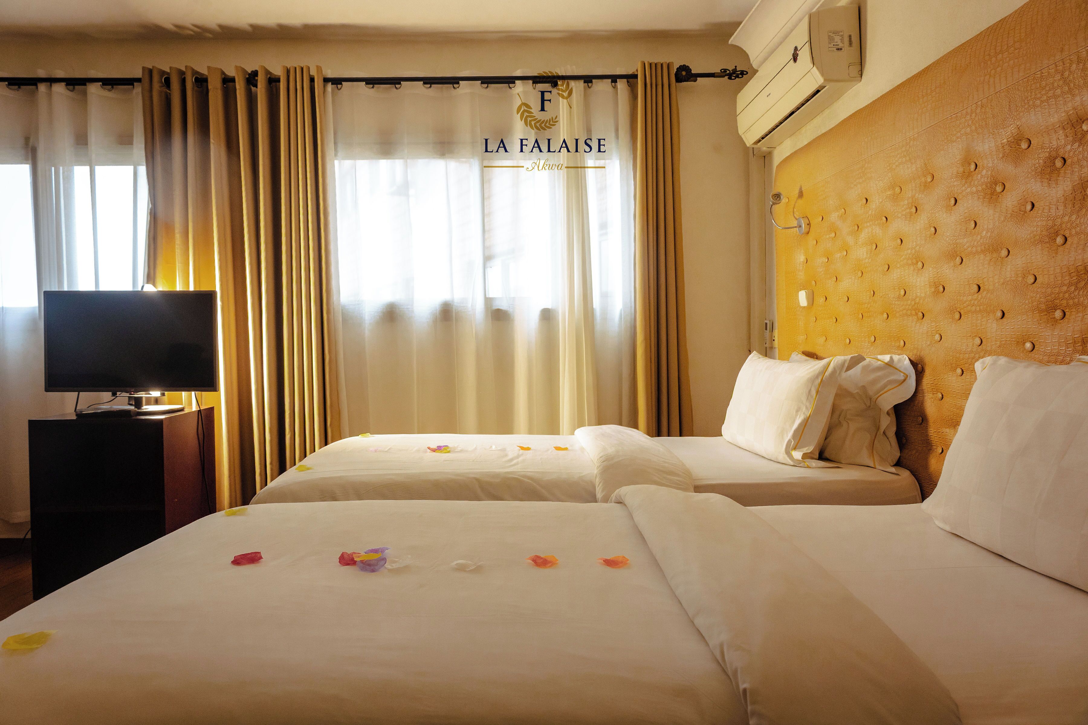 A hotel room with two beds, a television on a side table, and a sign reading 'LA FA LAISE'.
