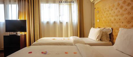 A hotel room with two beds, a television on a side table, and a sign reading 'LA FA LAISE'.