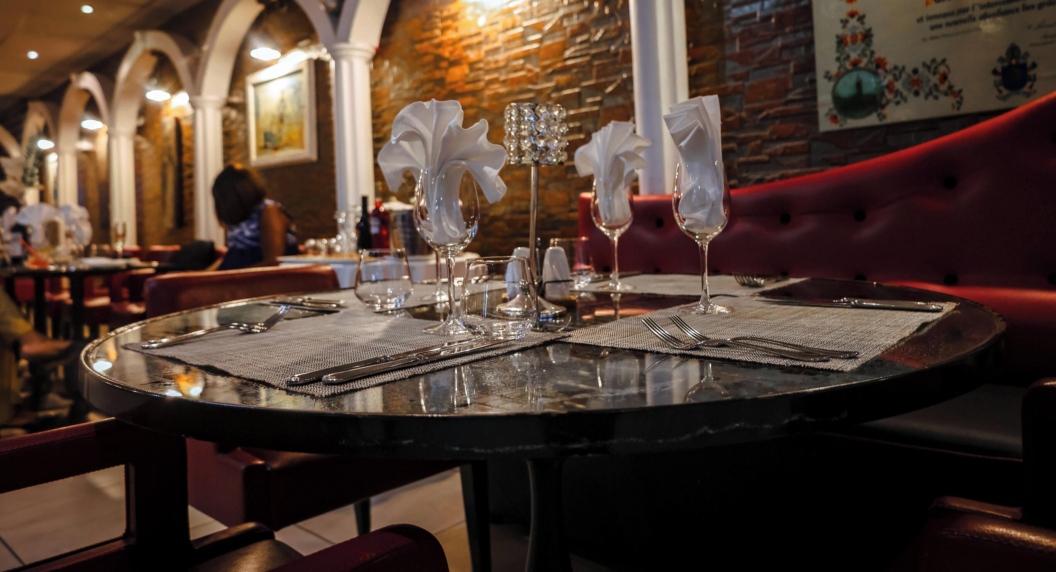 Un tavolo da ristorante apparecchiato con tovaglioli bianchi, bicchieri trasparenti e un menu.