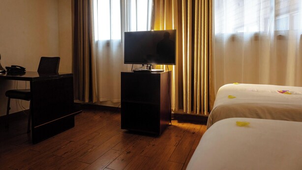 Habitación de hotel con escritorio, televisión y cama.