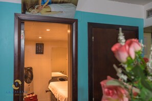 Una habitación de hotel con una cama, un ventilador y un reloj en la pared.