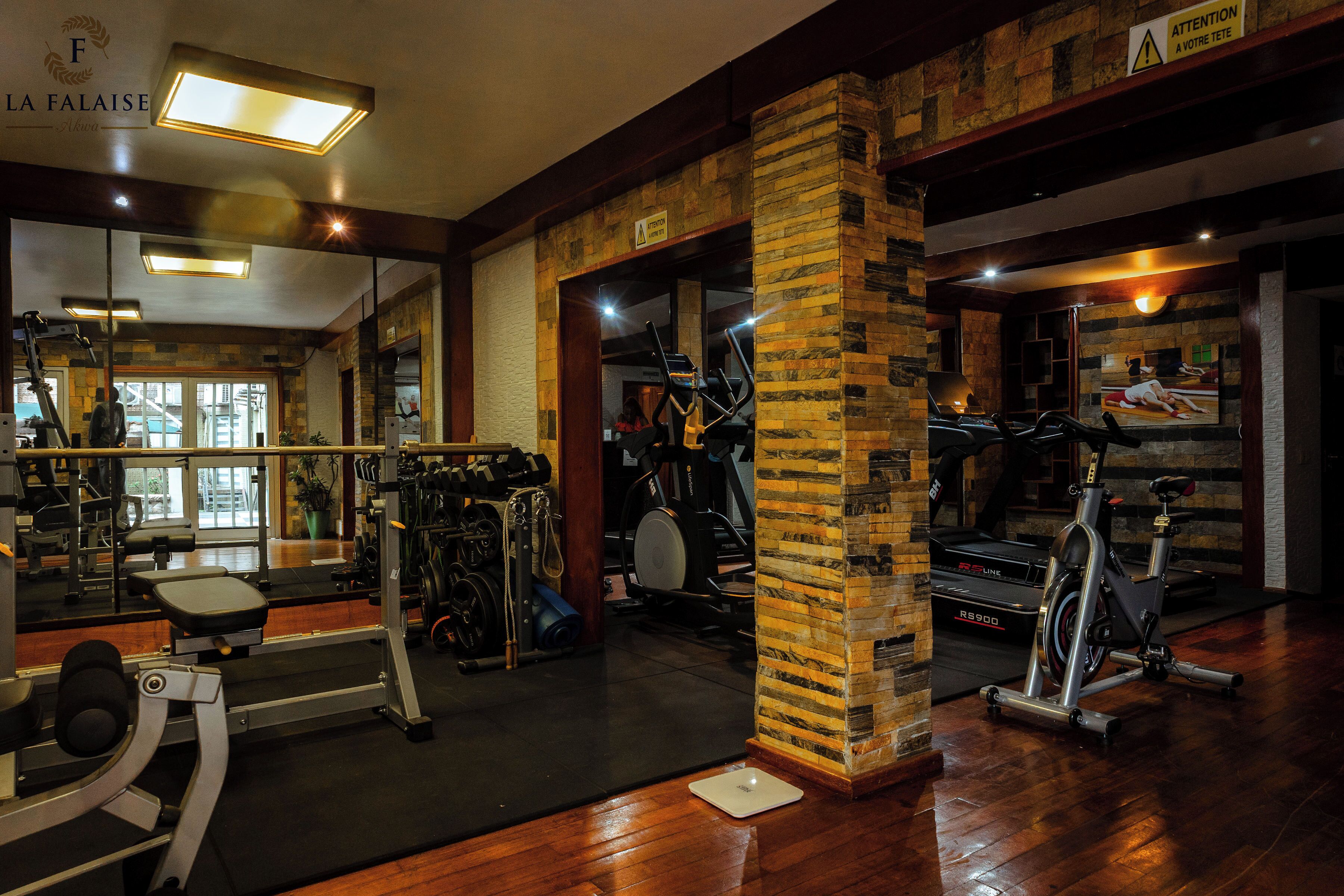 A gym with various exercise equipment, a mirror, and a wooden column.