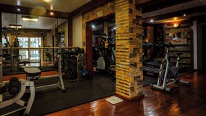 Un gimnasio con equipo de ejercicio variado, un espejo y un pilar de madera.