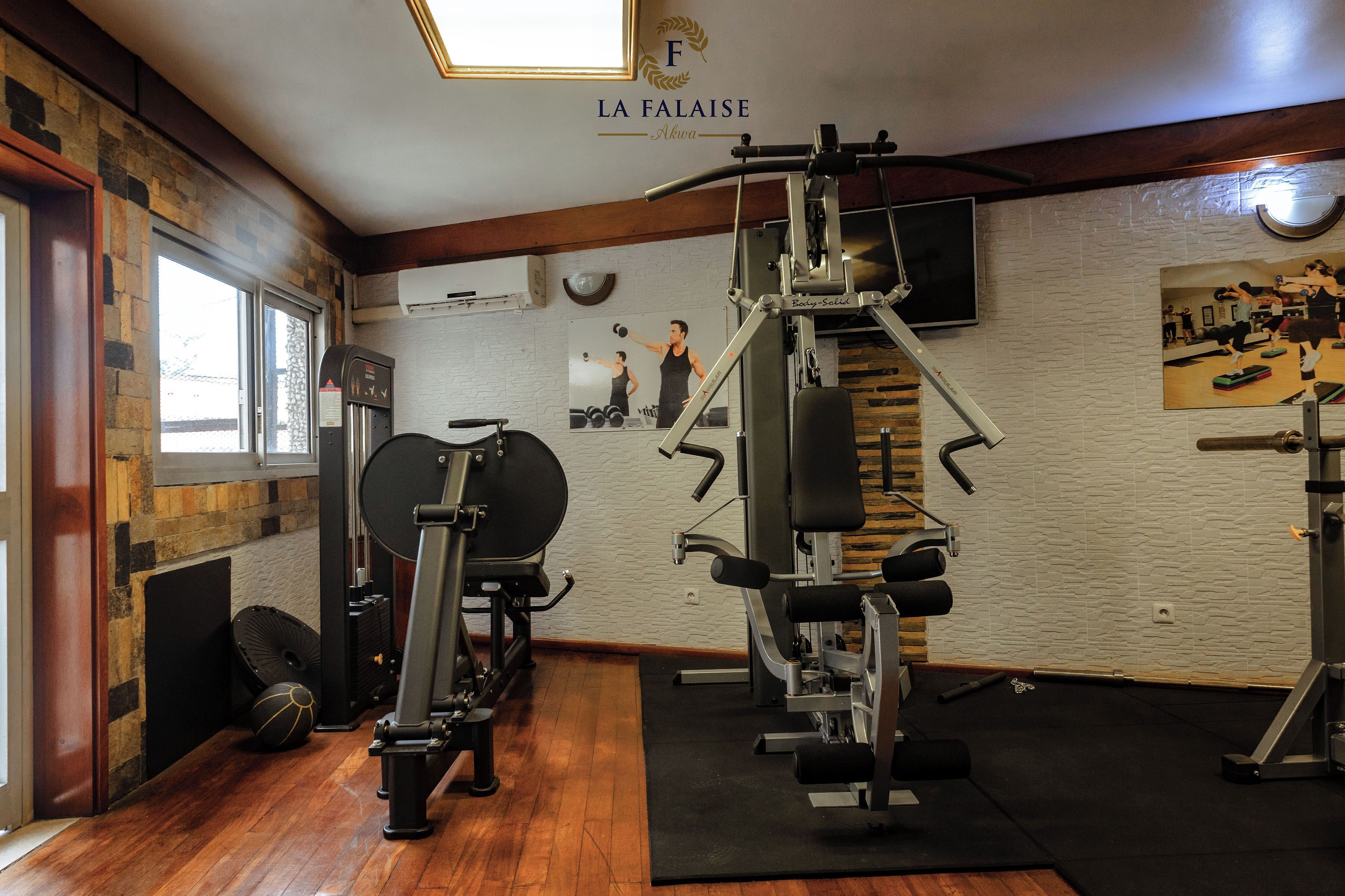 Un gimnasio con diferentes equipos de ejercicio, un espejo y un cuadro colgado en la pared.