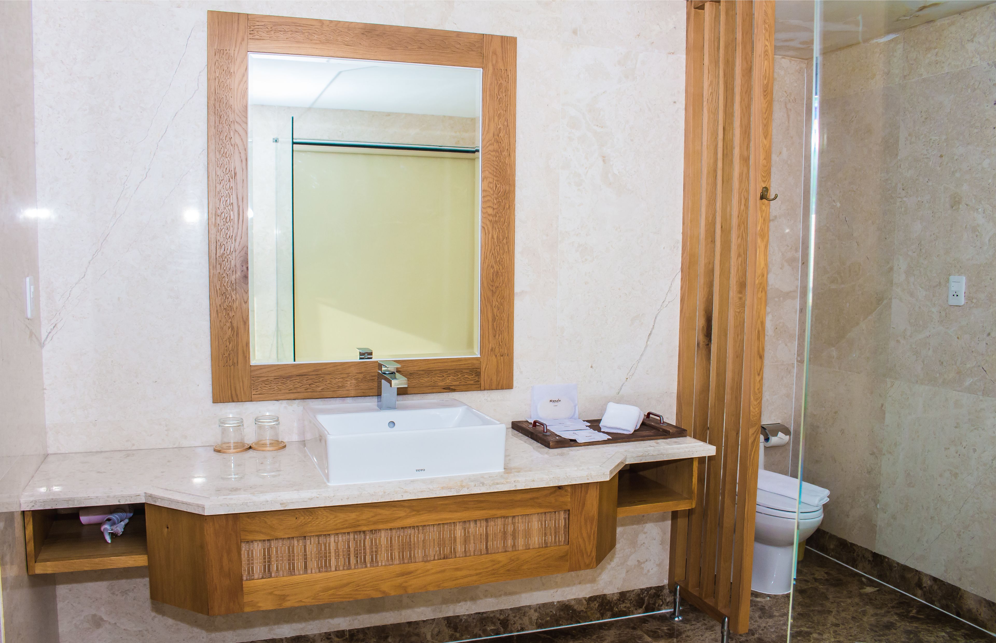 A bathroom with a wooden vanity, a large mirror, a sink, and a shower area.