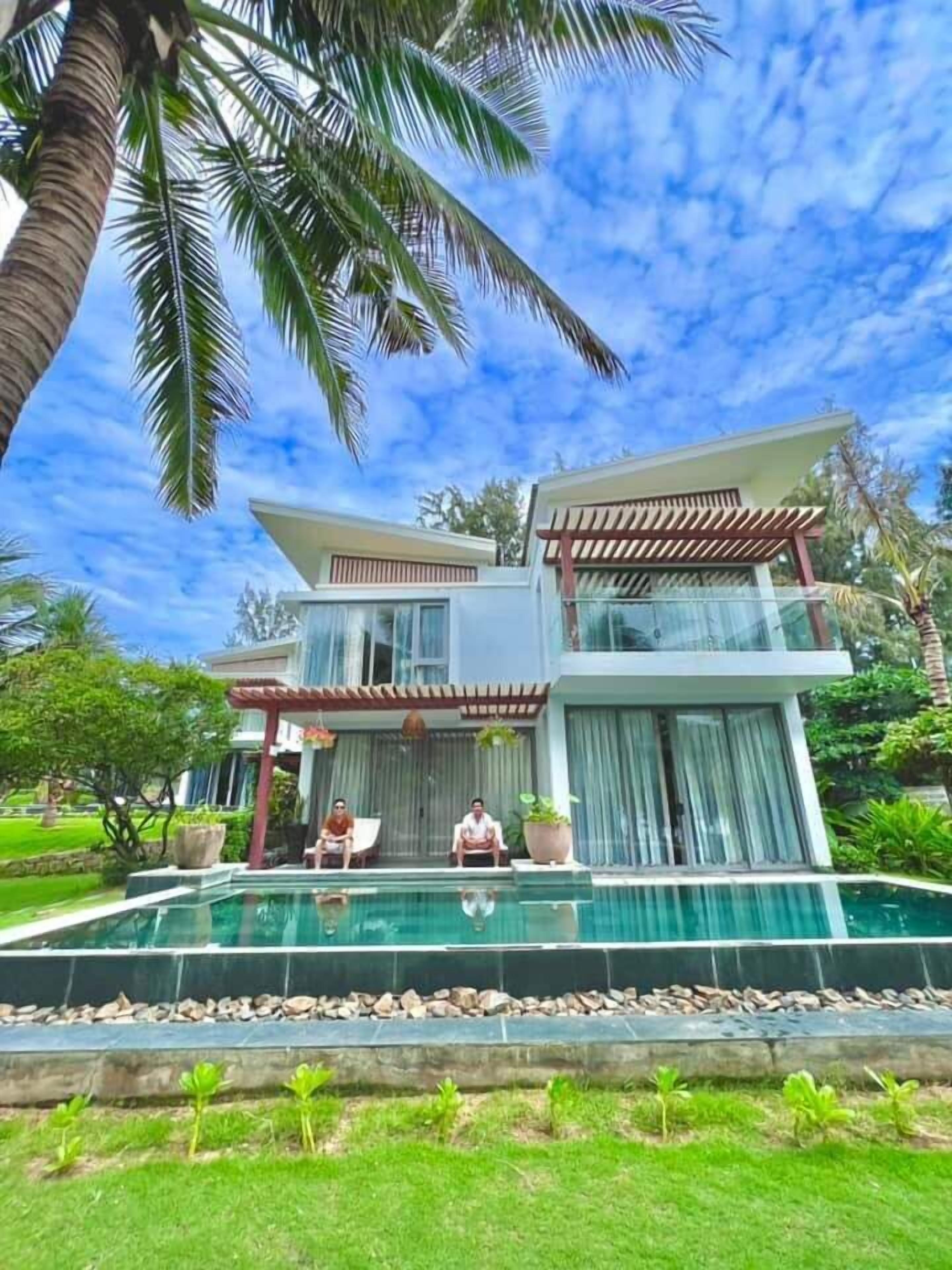 Una casa moderna de dos pisos con una amplia piscina delantera.
