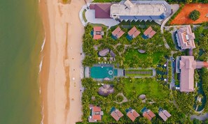 An aerial view of a resort with a beach, swimming pools, and multiple buildings with red roofs. - Sonata Resort & Spa (Tien Thanh)