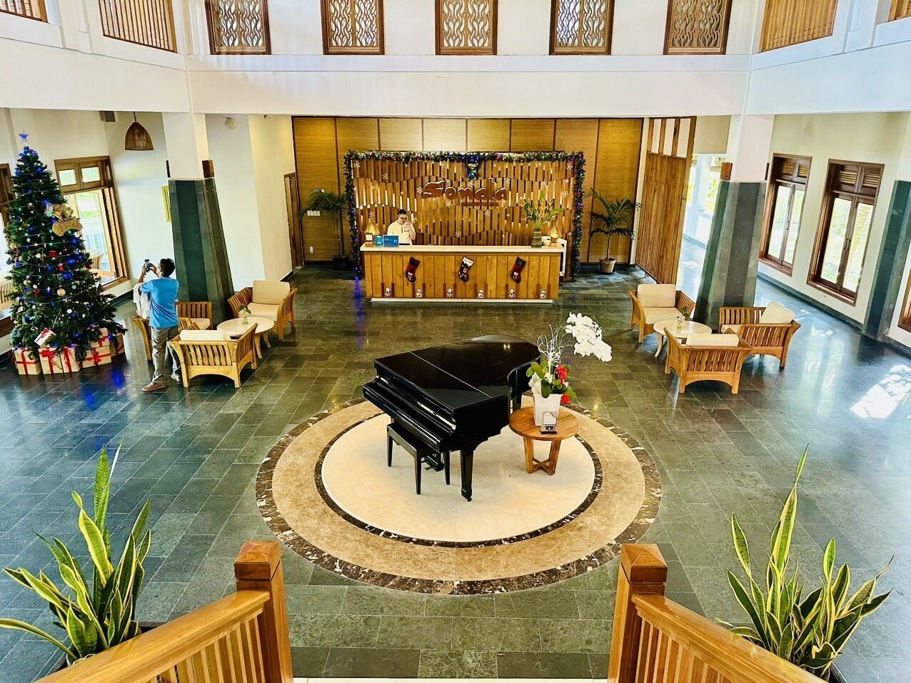 A lobby with a grand piano, a reception desk, and a Christmas tree.