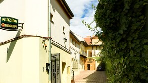 A narrow street with buildings on either side, a visible sign for 'Pension Krady', and a gate. - Penzión Hradby (Prešov)