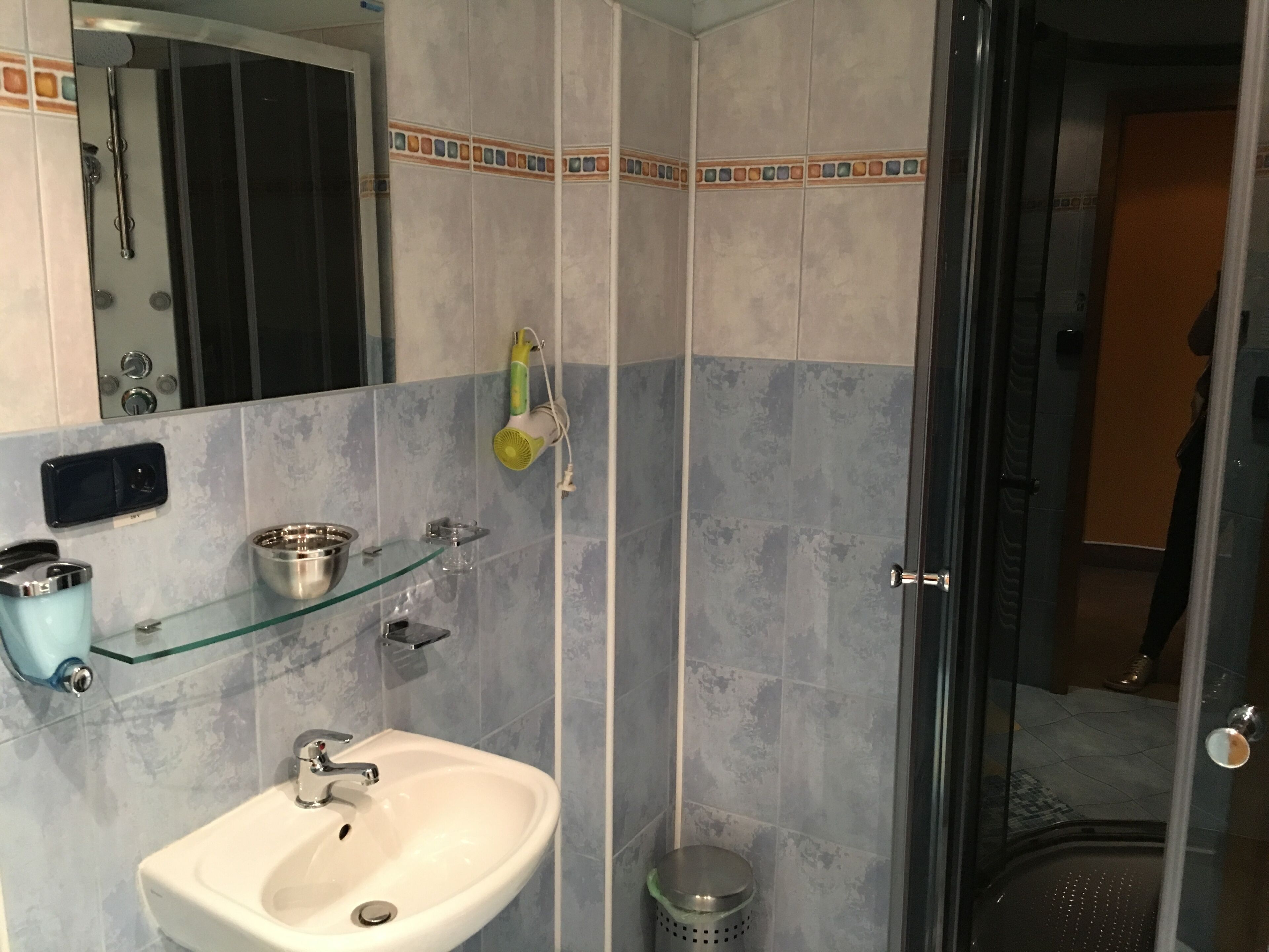 Une salle de bain avec une douche à parois de verre, un lavabo et un miroir.