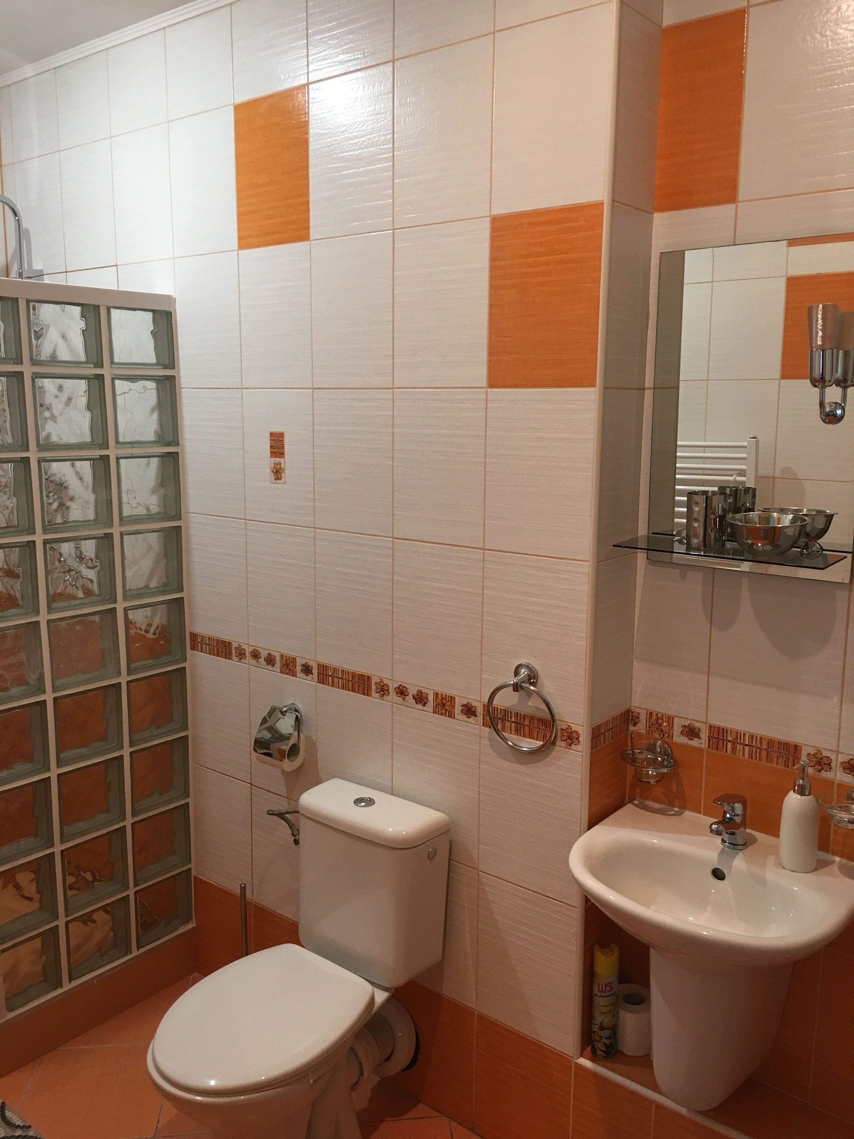 A bathroom with a toilet, sink, and mirror.