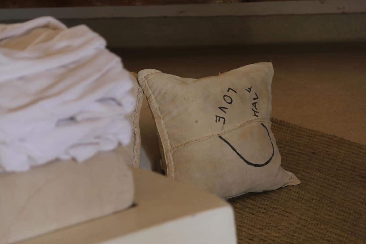 A bed with a pillow labeled "LOVE" and a folded white garment on the bed.