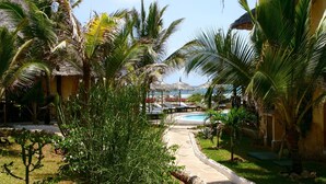 A resort with a pool, palm trees, and thatched-roof huts. - Mawe Resort Watamu Boutique Hotel (Watamu)