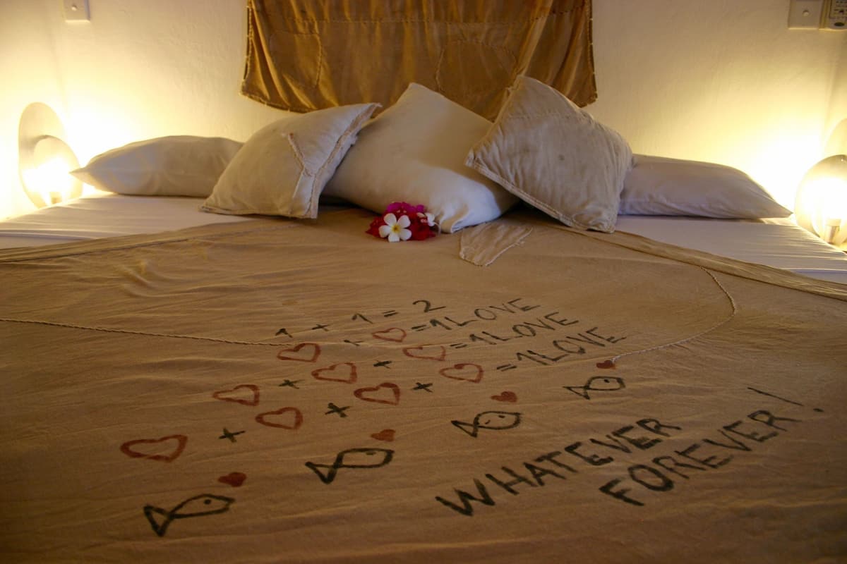 A bed with a message written on the bedspread that reads "WHATEVER LOVE FOREVER!" and various heart and star symbols.
