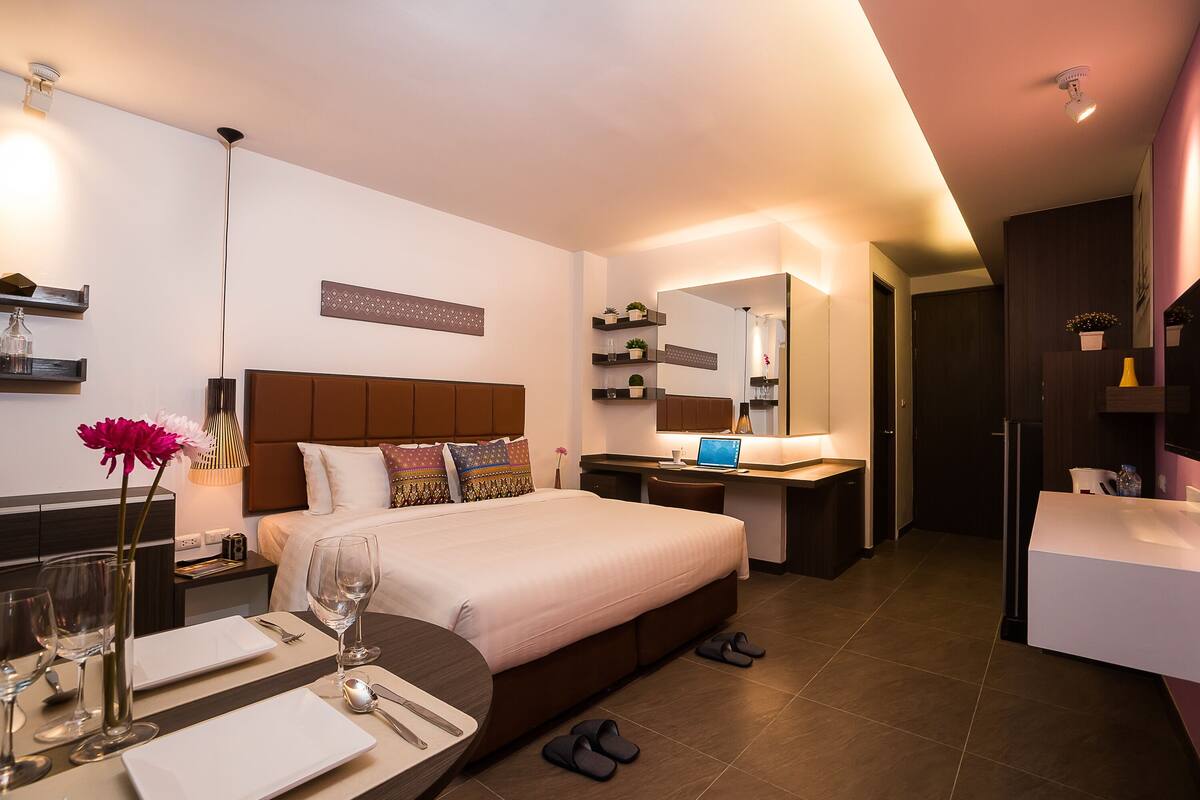 Een moderne hotelkamer met een groot bed, nachtkastje en een bureau met computer.