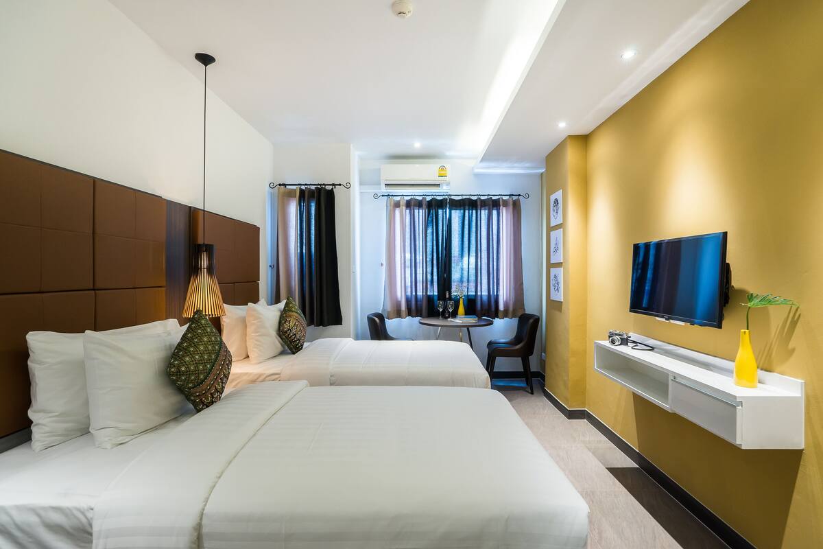 Een hotelkamer met twee bedden, een televisie, een bureau en een stoel.