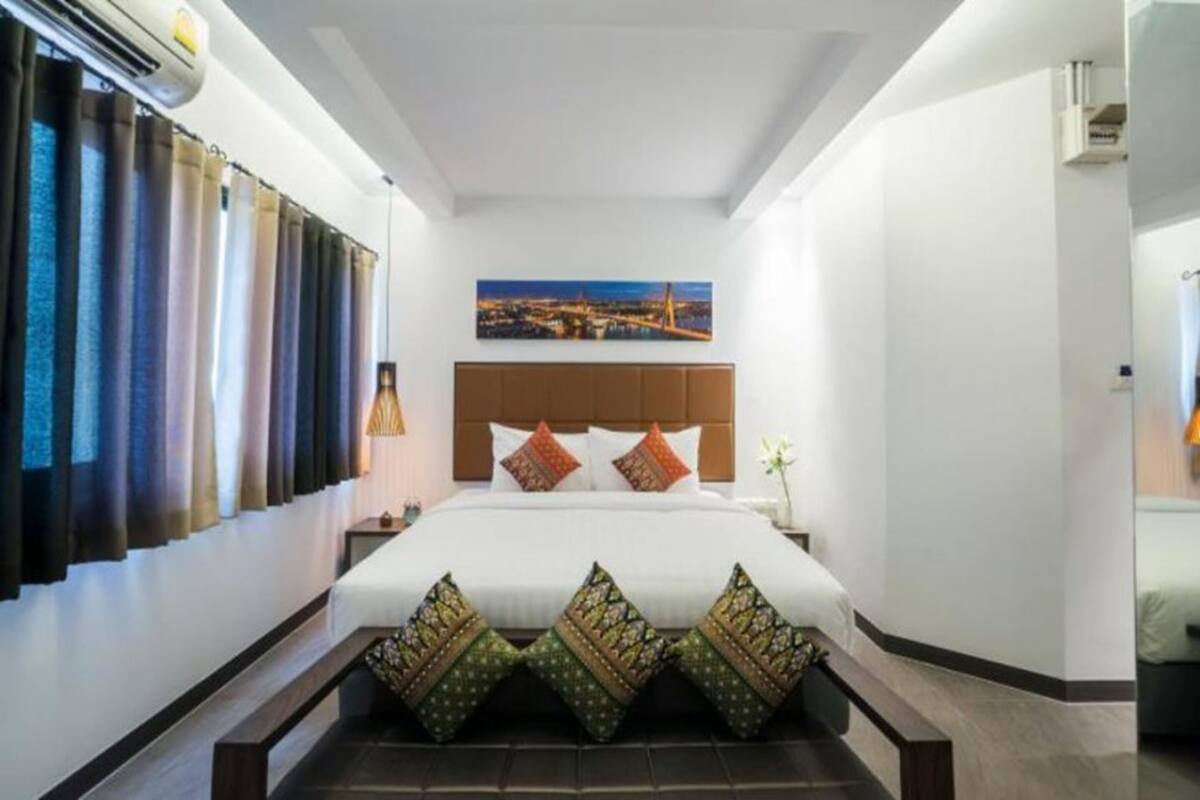 Een hotelkamer met een groot bed, een stadslandschap schilderij en uitzicht op de stad vanuit het raam.