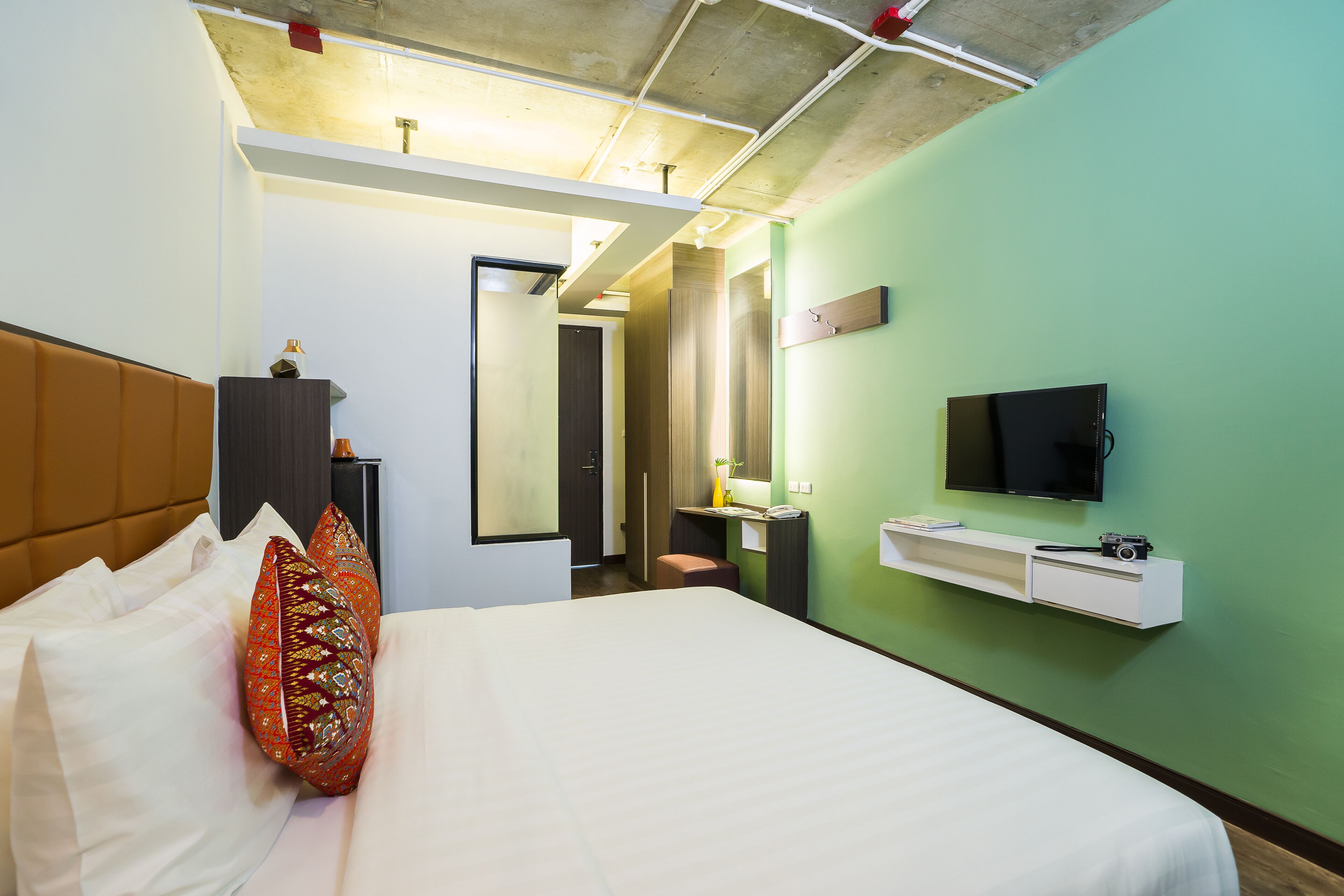 Una habitación de hotel con cama, televisión, escritorio y espejo.