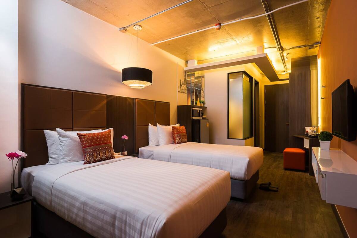 Een hotelkamer met twee bedden, een bureau, een spiegel en een televisie.