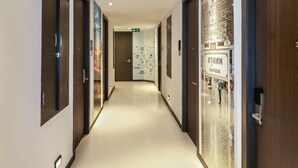 Un pasillo de hotel con puertas de madera, piso pulido y una pared con un mapa y un letrero.