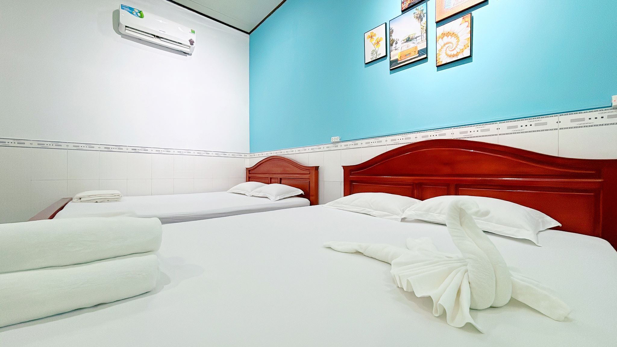A hotel room with two beds, white linens, a red headboard, and a blue accent wall.
