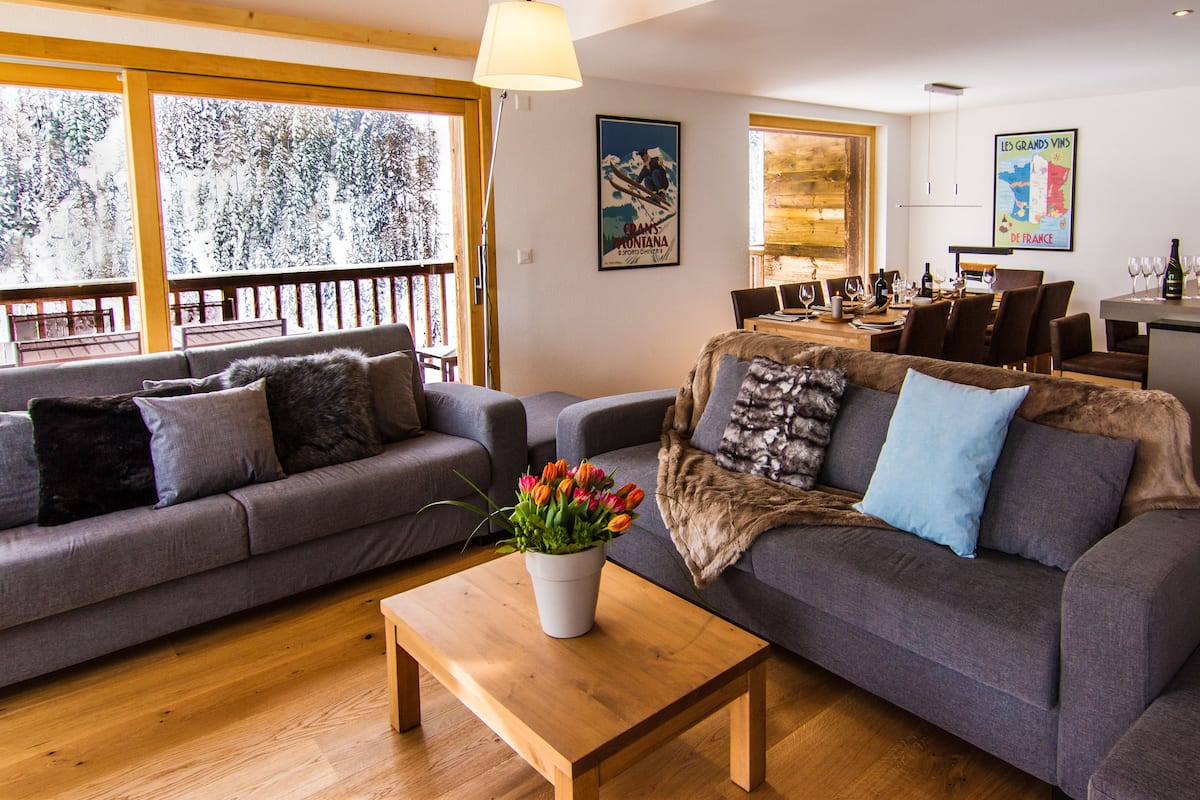 A modern living room with a grey sofa, a wooden coffee table, and a flower vase.