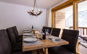 Une table à manger dressée avec des assiettes, des verres et une bouteille, entourée de chaises rembourrées.