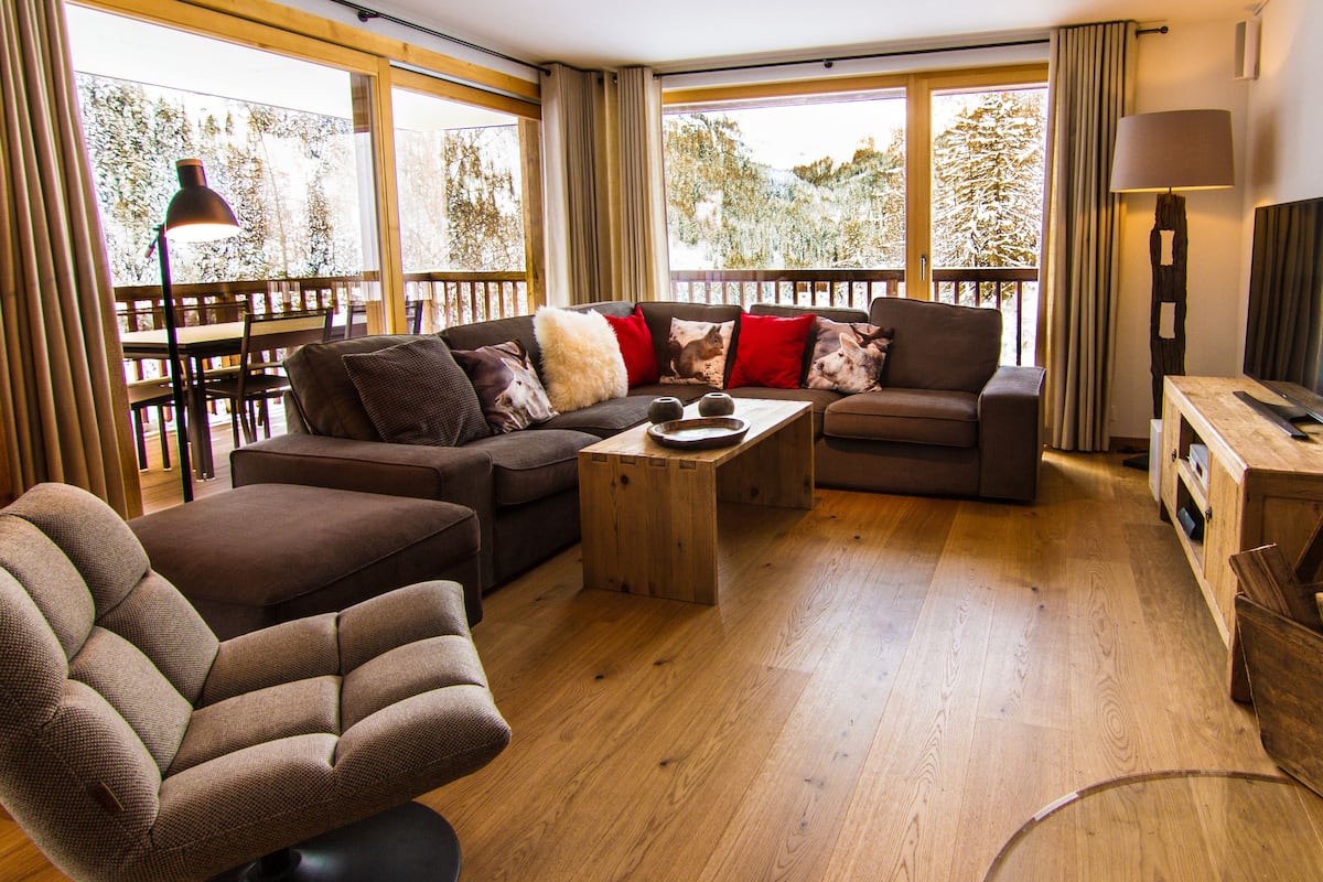 A modern living room with a sofa set, a coffee table, a television, and a fireplace.