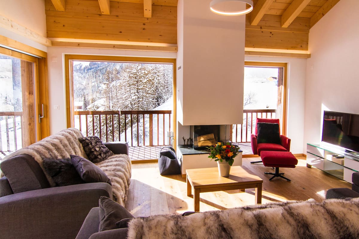 A cozy living room with a fireplace, a red armchair, and a television.