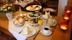Una mesa de desayuno con diversos alimentos, una tetera, una taza de café y candelabros decorativos.
