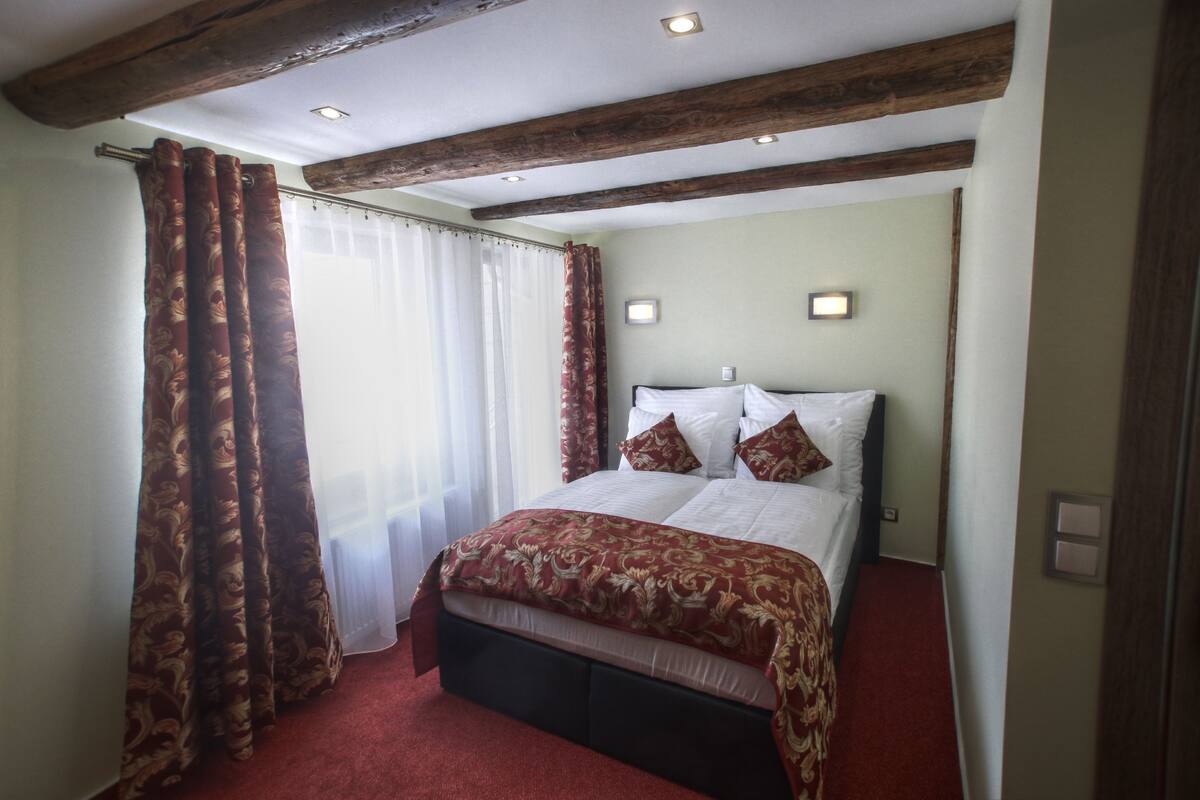 Habitación de hotel con una cama grande, techo de madera y alfombra roja.