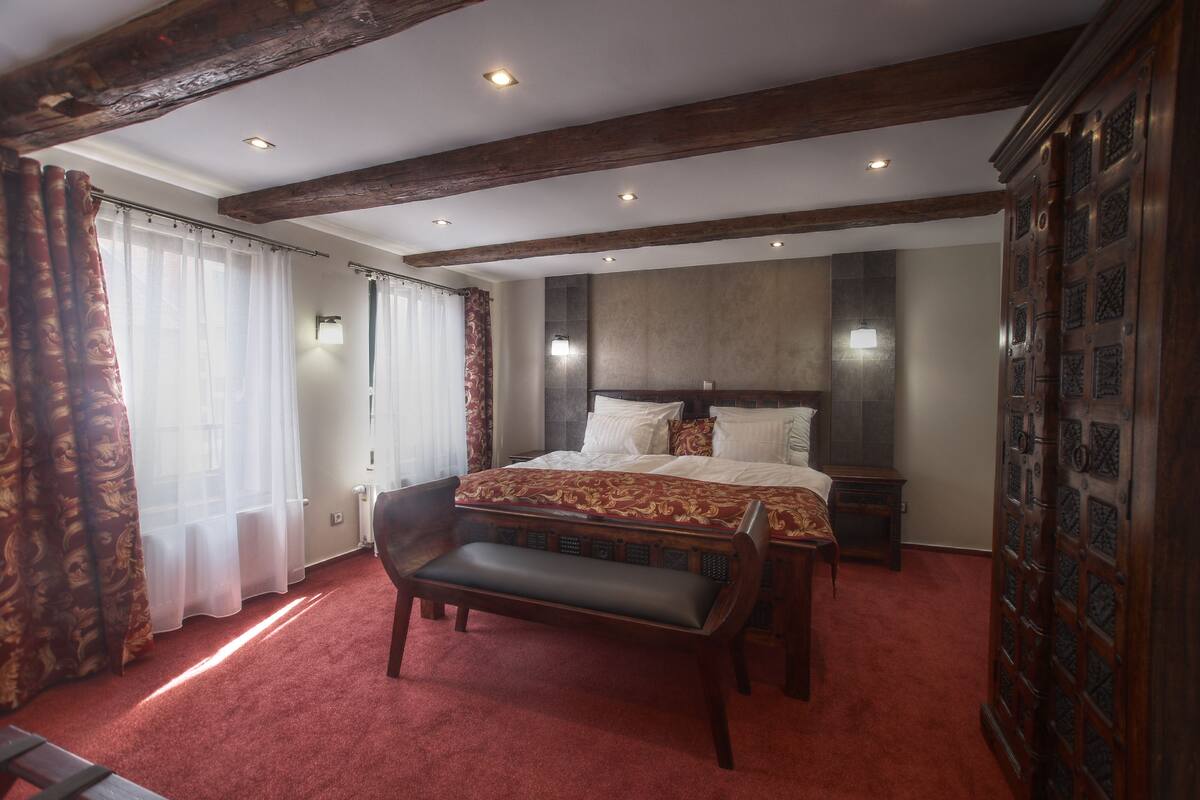 Un dormitorio con una cama grande, un banco, un armario de madera y un radiador.