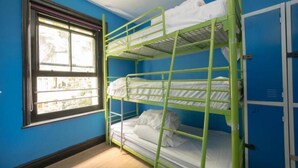 A bunk bed room with blue walls and a window. - Phoenix Hostel (London)