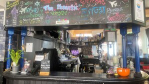 A reception desk with a chalkboard displaying 'The Phoenix' and various messages. - Phoenix Hostel (London)