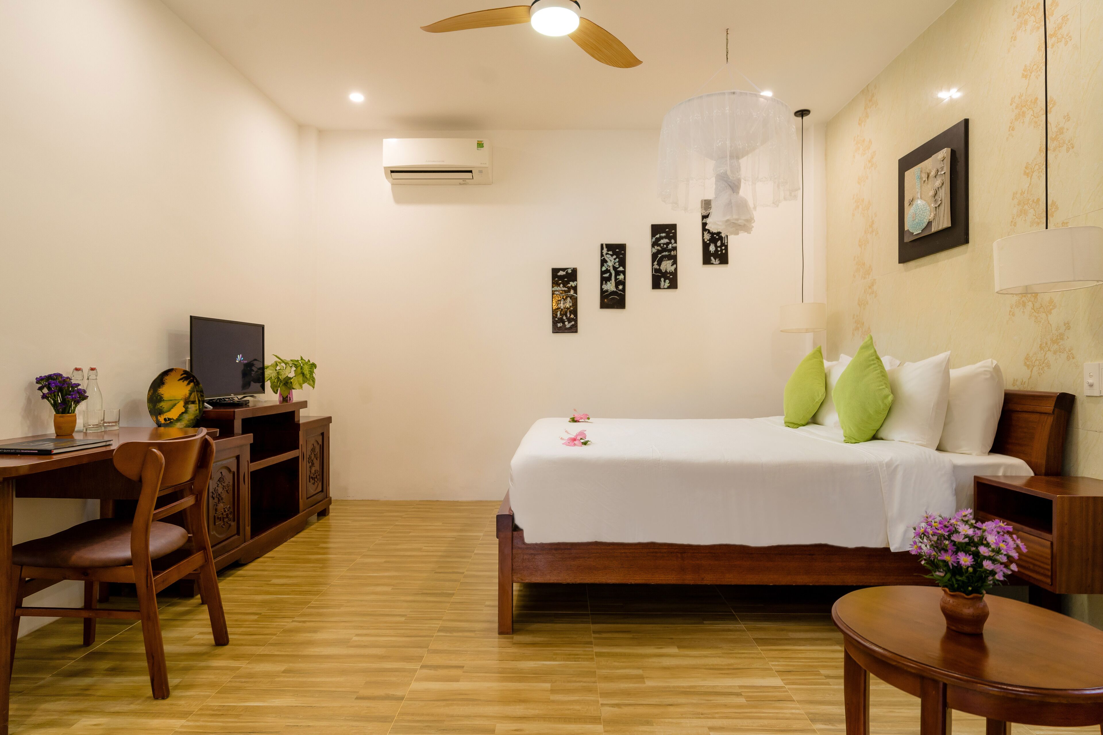 A hotel room with a bed, a desk, a chair, and a small table.