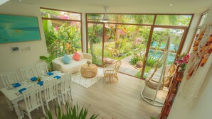 A spacious room with a large sliding glass door leading to a lush garden and pool area. - An Bang Garden Homestay (Da Nang)