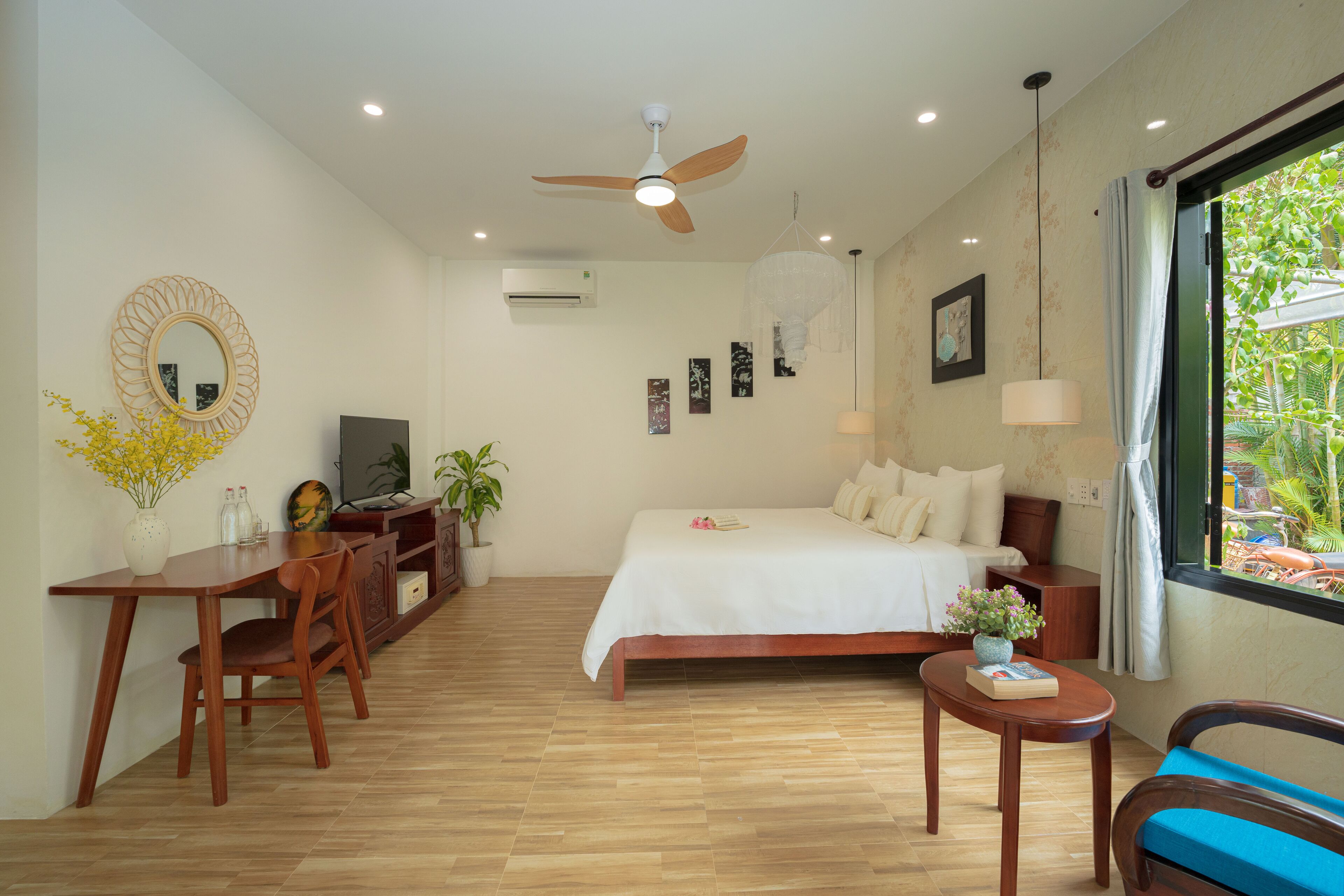 Une chambre à coucher comprenant un lit, un bureau, une chaise, un ventilateur de plafond et une fenêtre donnant sur un paysage verdoyant.