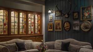 Un salon chaleureux avec deux canapés, une table basse et un buffet aux vitraux rempli de verrerie colorée.