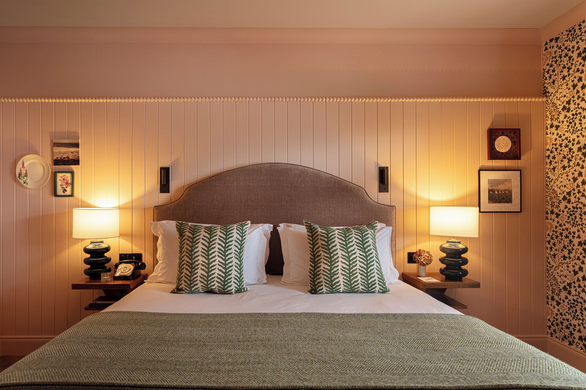 A hotel room with a bed, two nightstands, a headboard, and wall-mounted lamps.