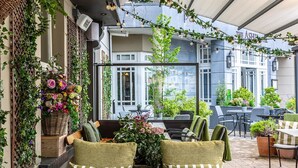 Un espace extérieur aménagé avec des canapés et des fauteuils confortables, entouré de verdure et de plantes en pot.