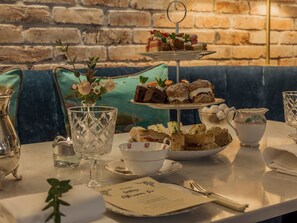 A table set with a tiered dessert stand, a floral vase, a teapot, and a menu. - The Ashe Hotel (Tralee)