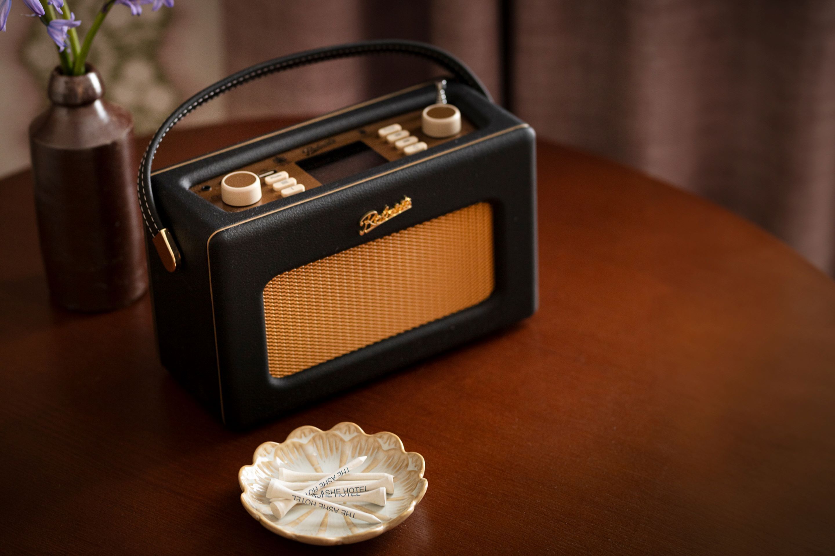 Una radio antigua con diseño negro y naranja, sobre una mesa de madera.