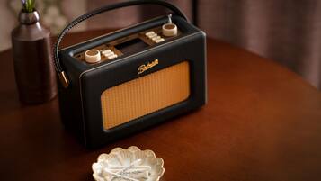 Una radio antigua con diseño negro y naranja, sobre una mesa de madera.
