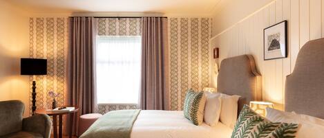 Habitación de hotel con dos camas, un televisor, una mesita con lámpara y una ventana con cortinas.