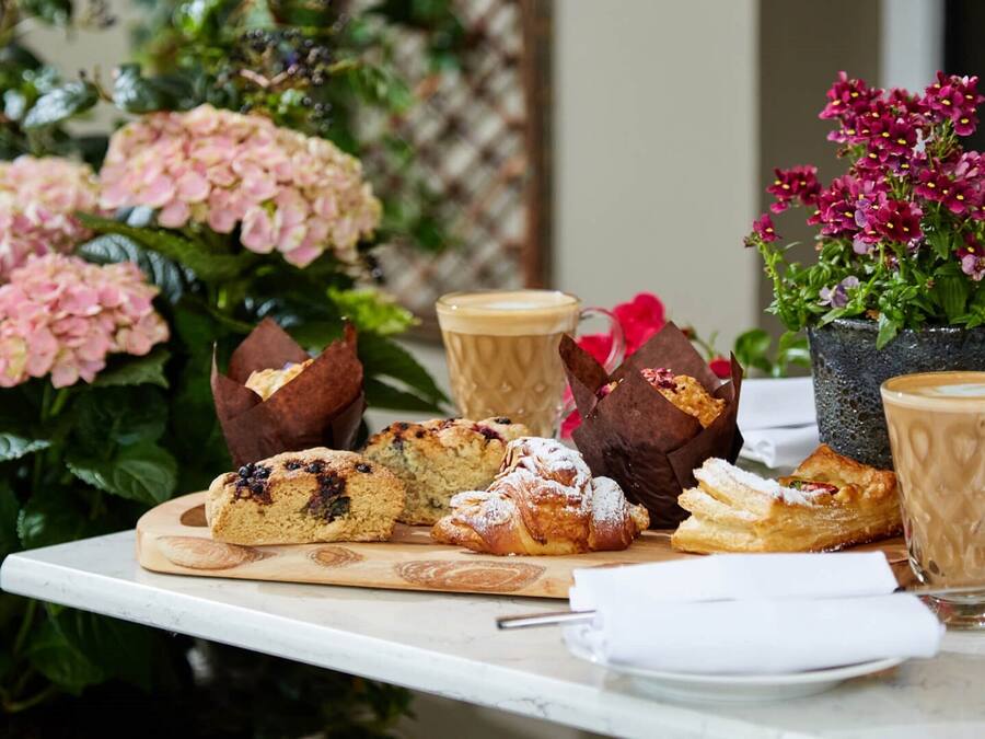 A table with pastries, a coffee cup, and a potted plant.