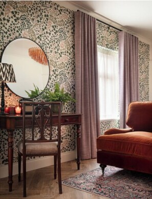 A room with a wooden chair, a round mirror, a desk, a red sofa, and a patterned rug. - The Ashe Hotel (Tralee)
