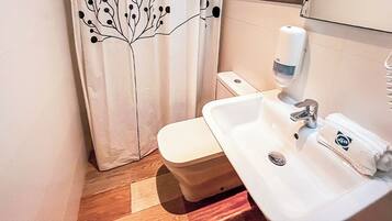 Un baño con inodoro, lavabo y dispensador de jabón para manos.