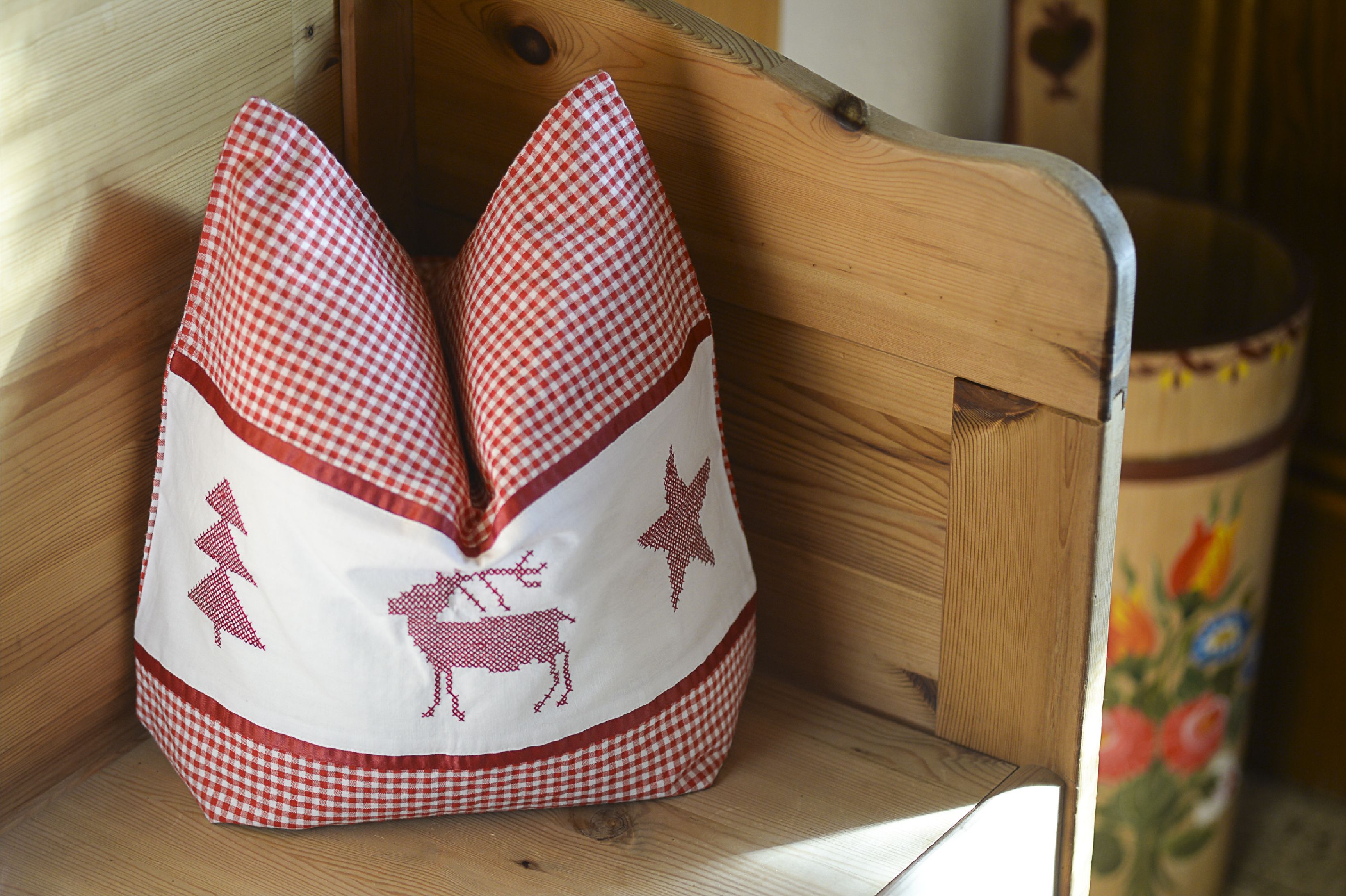 A checkered cushion with animal patterns on a wooden bench.