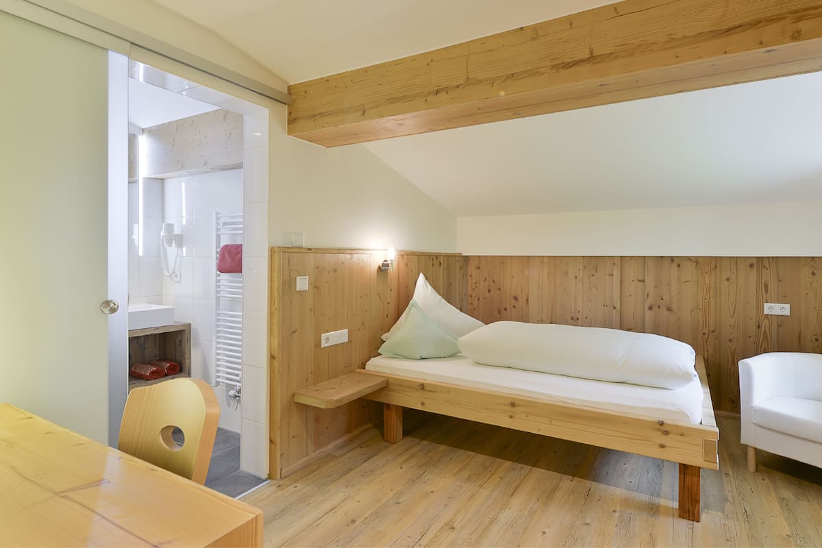 A compact bedroom with a wooden bunk bed, a small bedside table, and a chair.